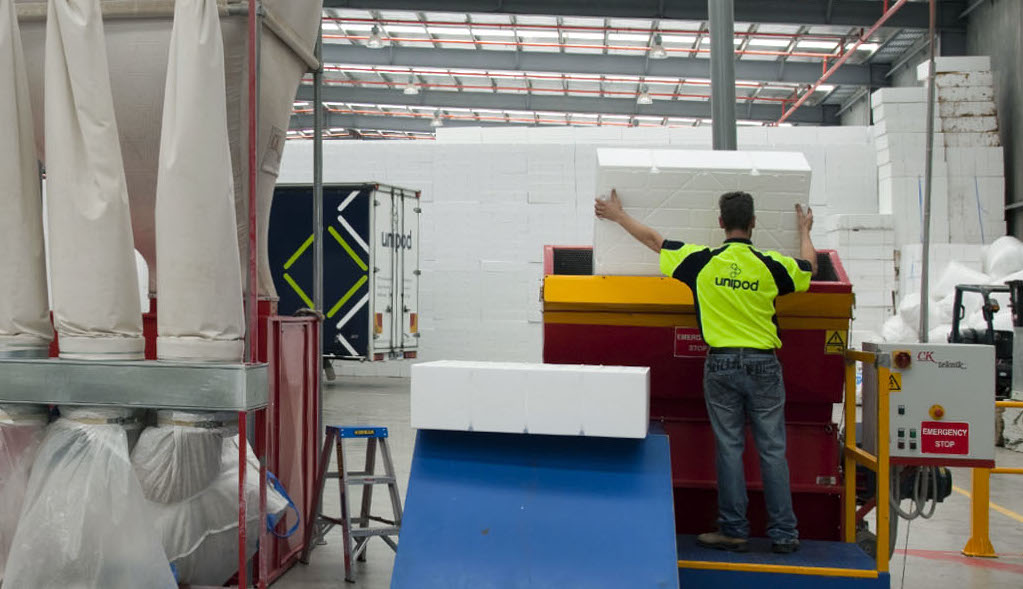 Expanded Polystyrene Recycling Worker guiding a waffle pod into an expanded polystyrene recycling machine